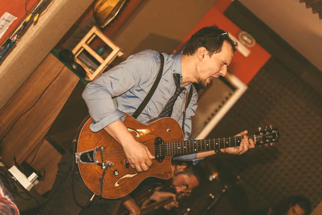 The guitarist playing a red semi-hollow guitar, shot from above