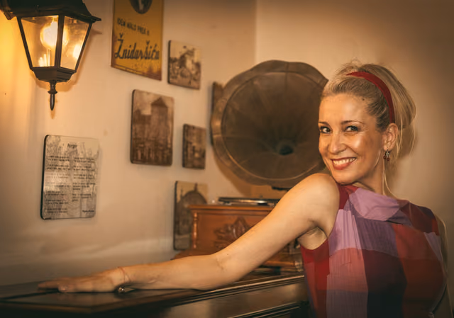 The singer smiling beside an old record player