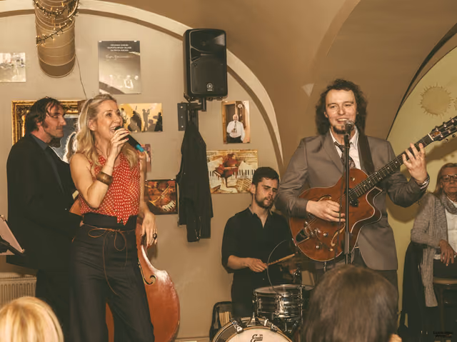 The band playing in a vaulted tavern, singer and guitarist at their microphones