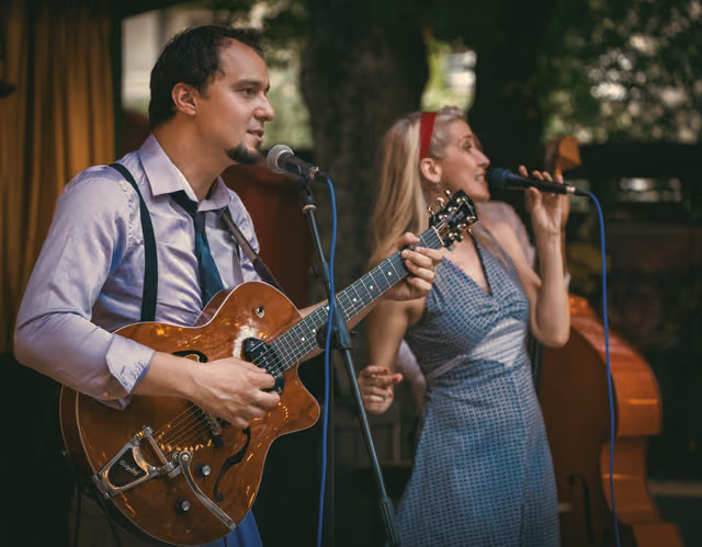 The guitarist and the singer in a duet, each at their own microphone