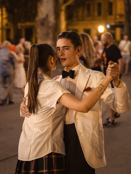 A couple dancing at an evening dance in the park, he in a white jacket