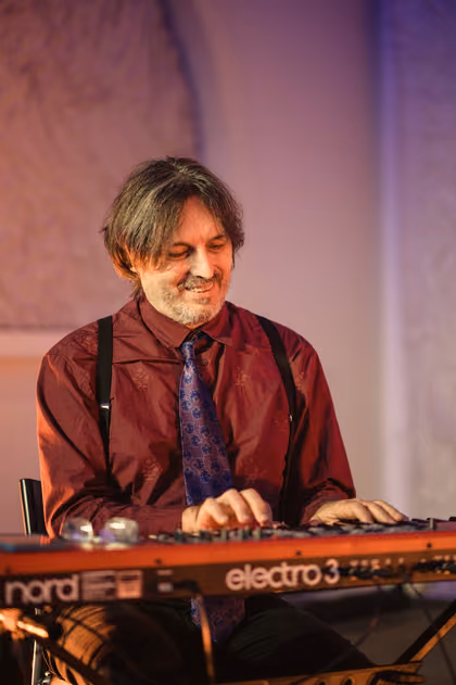 The keyboard player in a red shirt and tie at red keys