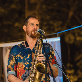 The saxophonist playing outdoors